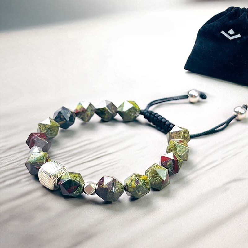 Man rock climbing wearing Dragon Blood Stone bracelet for Root Chakra stability and fearless courage during extreme adventures
