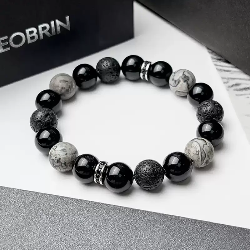10mm Obsidian (protection) and Volcanic Stone (earth energy) bracelet on a hiker’s wrist – embodies courage to explore uncharted trails and absorb negative energy during outdoor adventures.