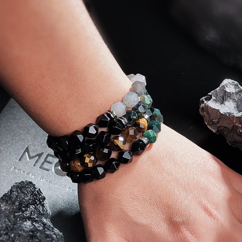 Person meditating in forest with Dendritic Agate bracelet for Heart Chakra peace and Root Chakra stability