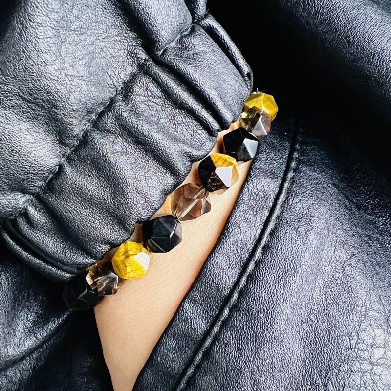 Person in meditation wearing Ice Obsidian bracelet for full chakra purification and Tiger’s Eye courage during spiritual practice